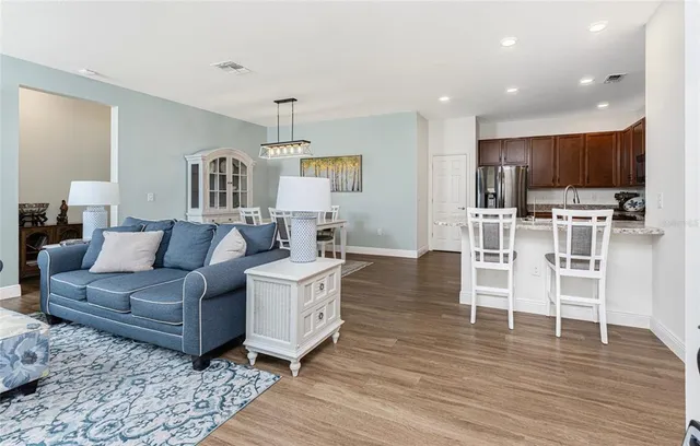 a living room with furniture a wooden floor and kitchen view