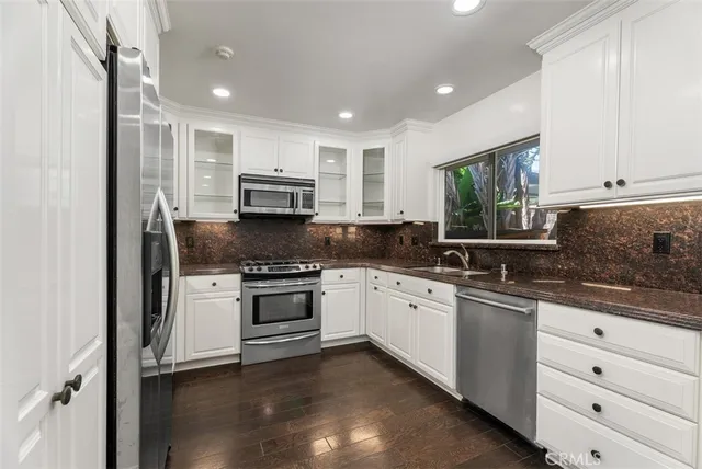 a kitchen with granite countertop white cabinets and stainless steel appliances