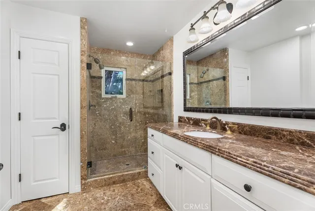 a bathroom with a granite countertop sink mirror and shower
