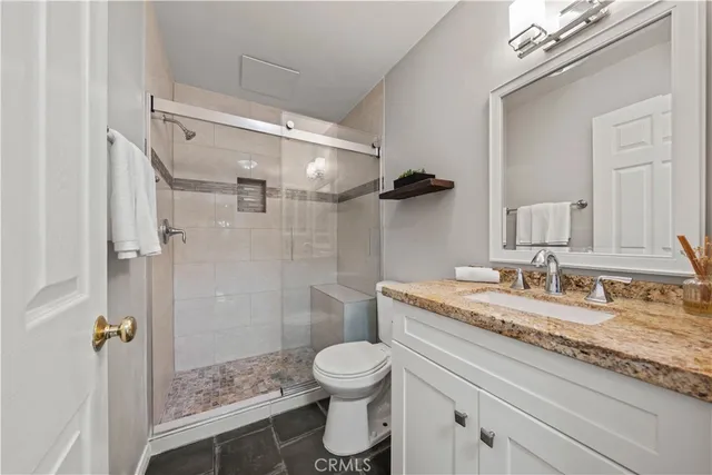 a bathroom with a granite countertop sink toilet a mirror and shower