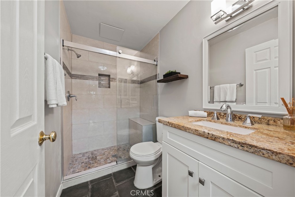 5215 Balboa Boulevard, Unit 203 Encino, CA 91316 - Photo 15 of 27 a bathroom with a granite countertop sink toilet a mirror and shower