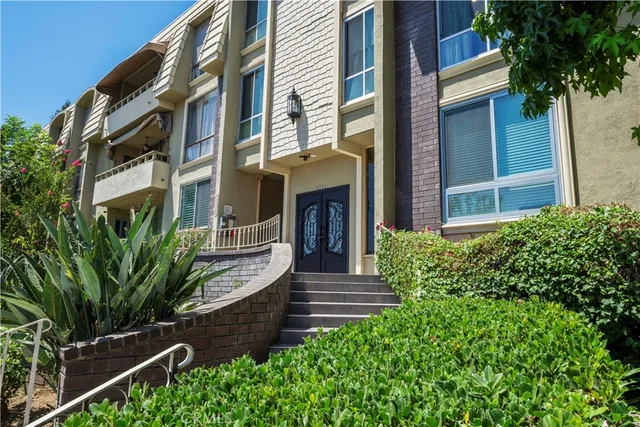 a view of a house with large windows and plants