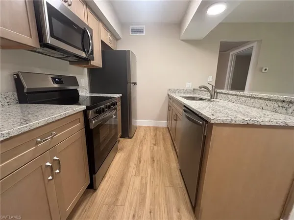 a kitchen with granite countertop stainless steel appliances and wooden cabinets