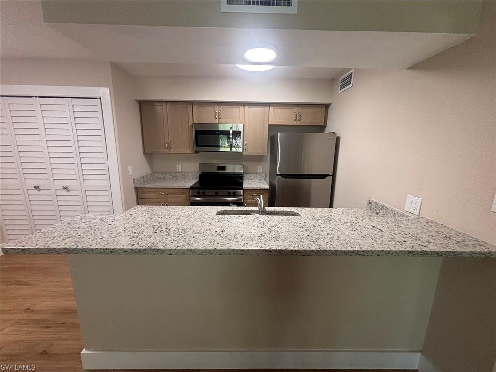 5305 Summerlin Road, Unit 501 Fort Myers, FL 33919 - Photo 5 of 10 a kitchen with kitchen island granite countertop counter top space cabinets and stainless steel appliances