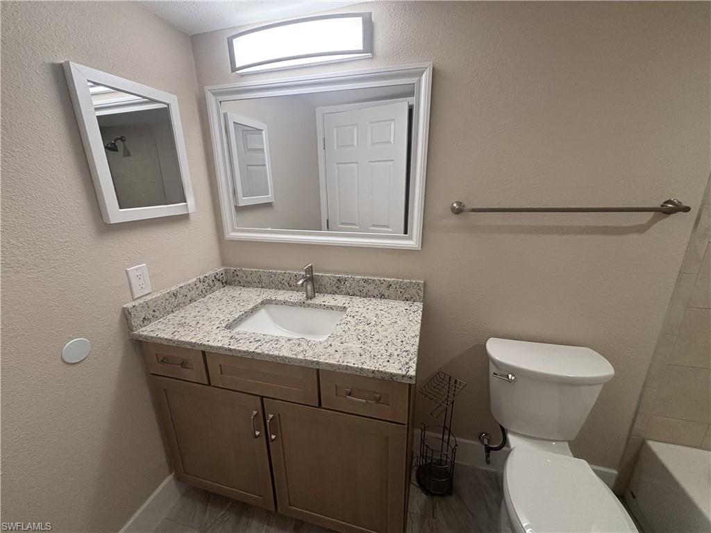 5305 Summerlin Road, Unit 501 Fort Myers, FL 33919 - Photo 10 of 10 a bathroom with a granite countertop toilet sink and mirror