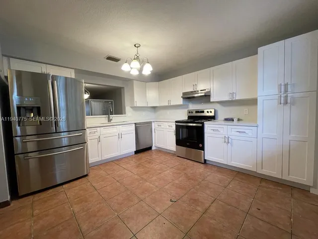 a kitchen with granite countertop stainless steel appliances and white cabinets