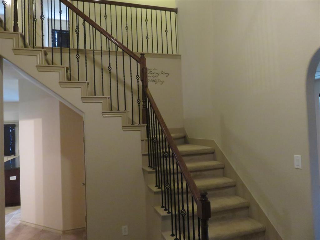 1122 Walter Stephenson Road Midlothian, TX 76065 - Photo 6 of 26 Dual-level staircase featuring carpeted treads and risers, wrought iron balusters with decorative elements, and a wood-finish handrail