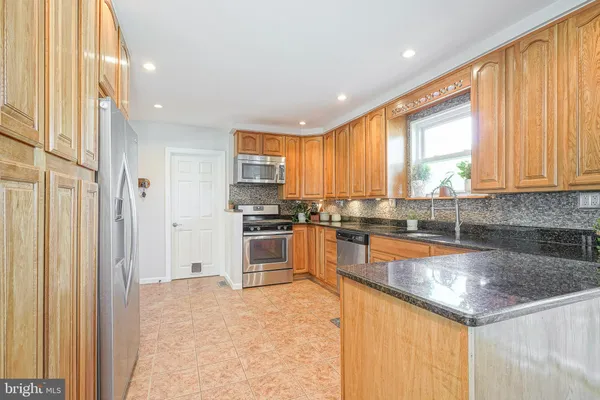 a kitchen with stainless steel appliances granite countertop a refrigerator a sink dishwasher a stove and white countertops with wooden floor