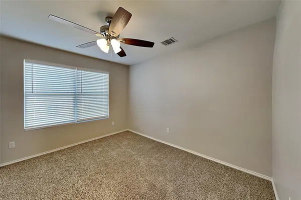 an empty room with a chandelier fan and windows