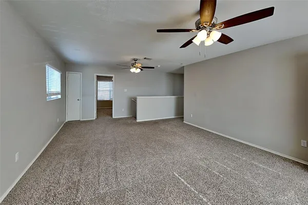 en empty room with windows and chandelier fan