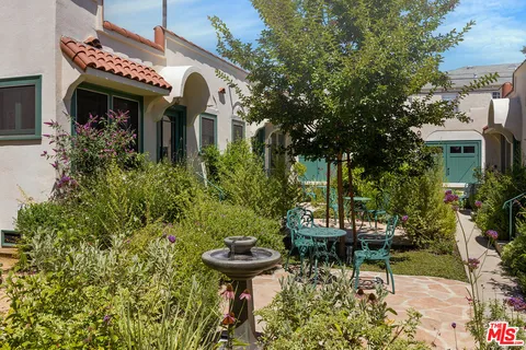 a front view of a house with fountain plants and trees