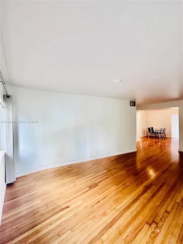 a view of a living room hardwood floor and a kitchen with a sink