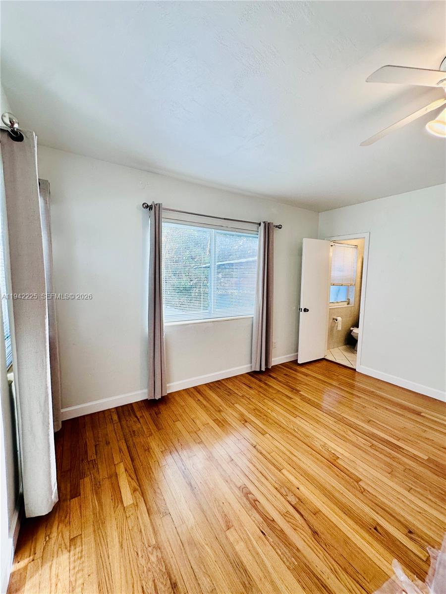 1180 Southwest 22nd Terrace, Unit 1 Miami, FL 33129 - Photo 20 of 32 a view of an empty room with wooden floor and a window