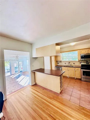 a living room with stainless steel appliances furniture a rug and a kitchen view