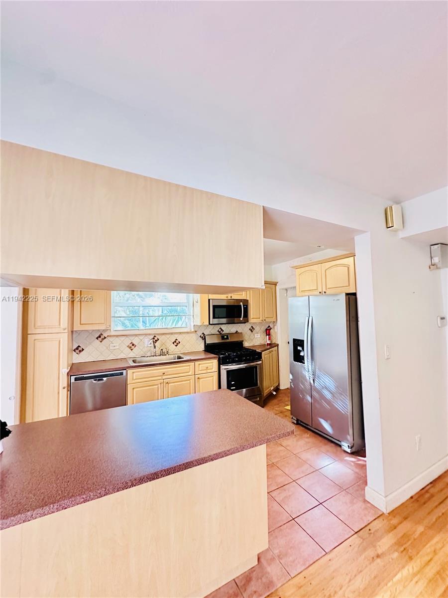 1180 Southwest 22nd Terrace, Unit 1 Miami, FL 33129 - Photo 6 of 32 a living room with stainless steel appliances furniture a rug and a kitchen view
