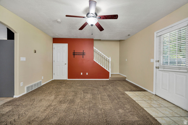 2 West 1780 North Logan, UT 84341 - Photo 10 of 24 Unfurnished living room featuring light colored carpet, a ceiling fan, light tile patterned floors, a textured ceiling, and arched walkways