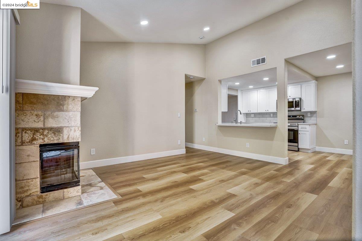 a view of kitchen with kitchen island wooden floor and a fireplace