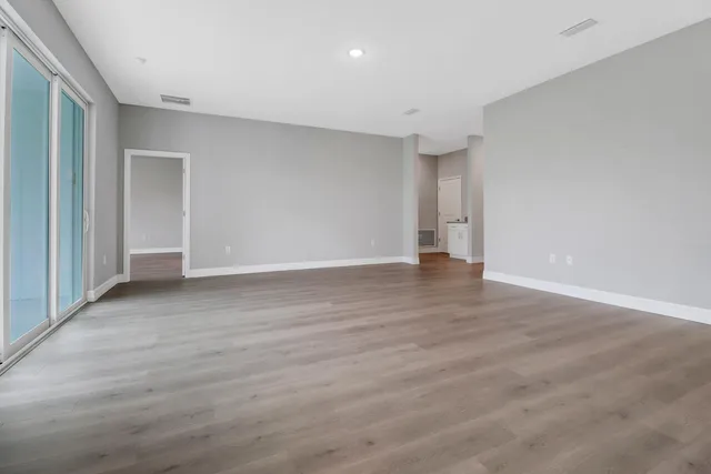 a view of an empty room with wooden floor and closet