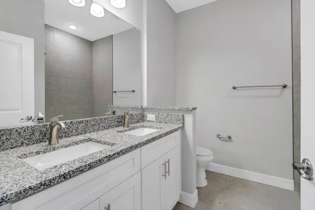 a bathroom with a granite countertop sink a toilet and a mirror