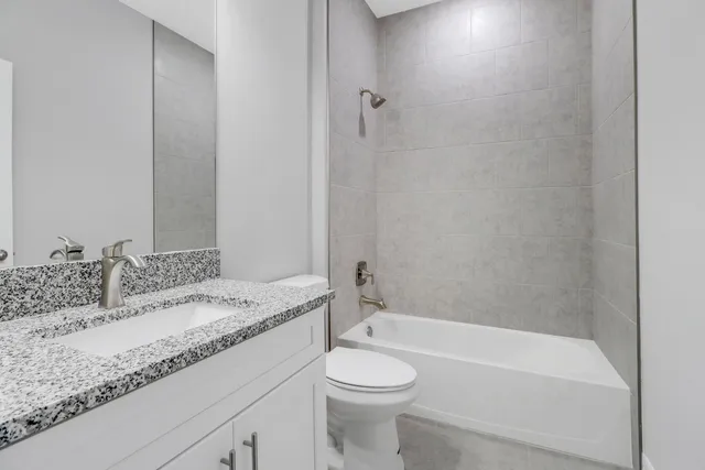 a bathroom with a granite countertop sink toilet and bathtub