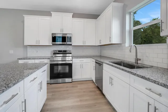 a kitchen with granite countertop white cabinets and white stainless steel appliances