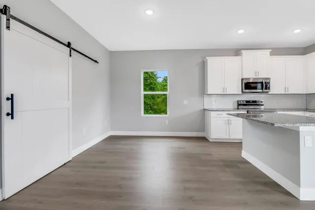 a kitchen with kitchen island white cabinets and wooden floor