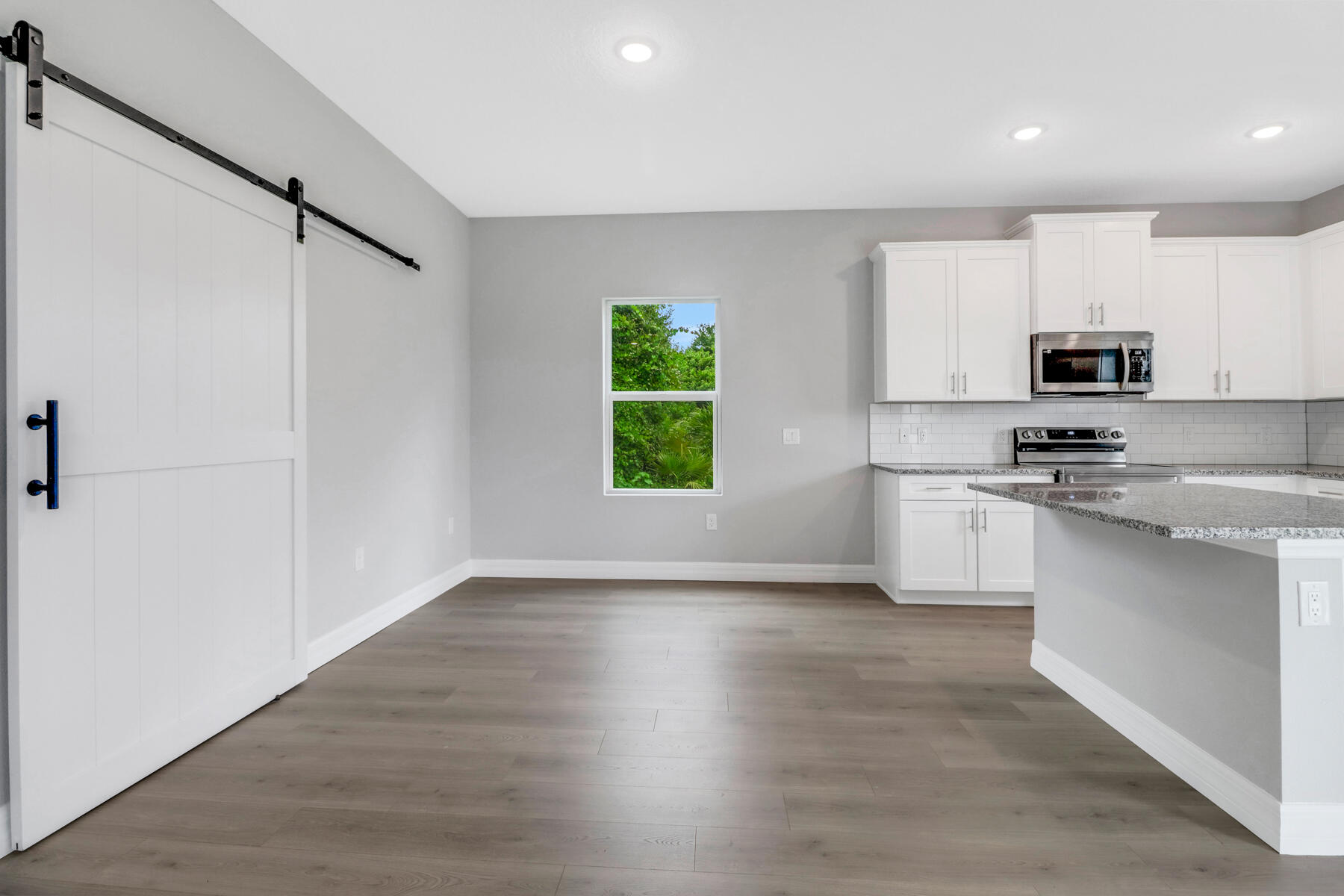 23158 Ranger Avenue Port Charlotte, FL 33954 - Photo 5 of 25 a kitchen with kitchen island white cabinets and wooden floor