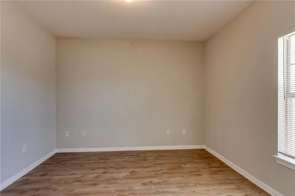 an empty room with chandelier fan and windows