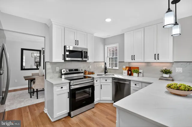 a kitchen with a sink a stove top oven and white cabinets