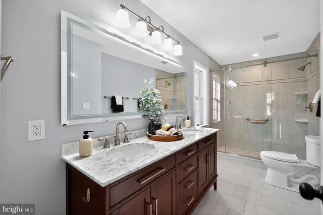 a bathroom with a granite countertop sink a toilet a mirror and shower