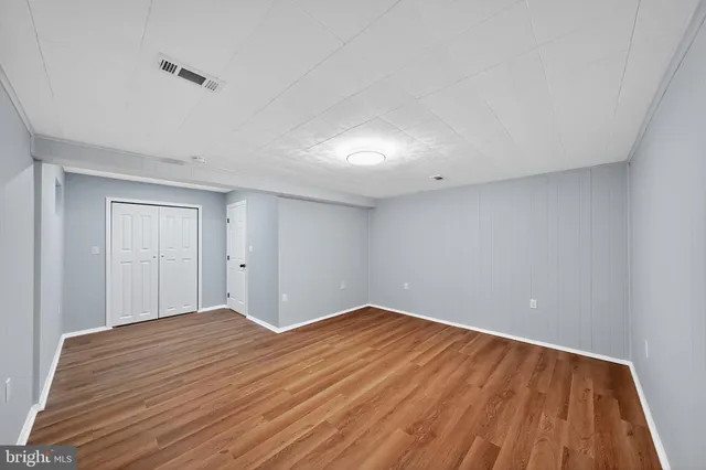 a view of empty room with wooden floor and fan