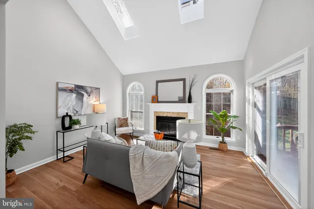 a living room with furniture a fireplace and a potted plant with wooden floor