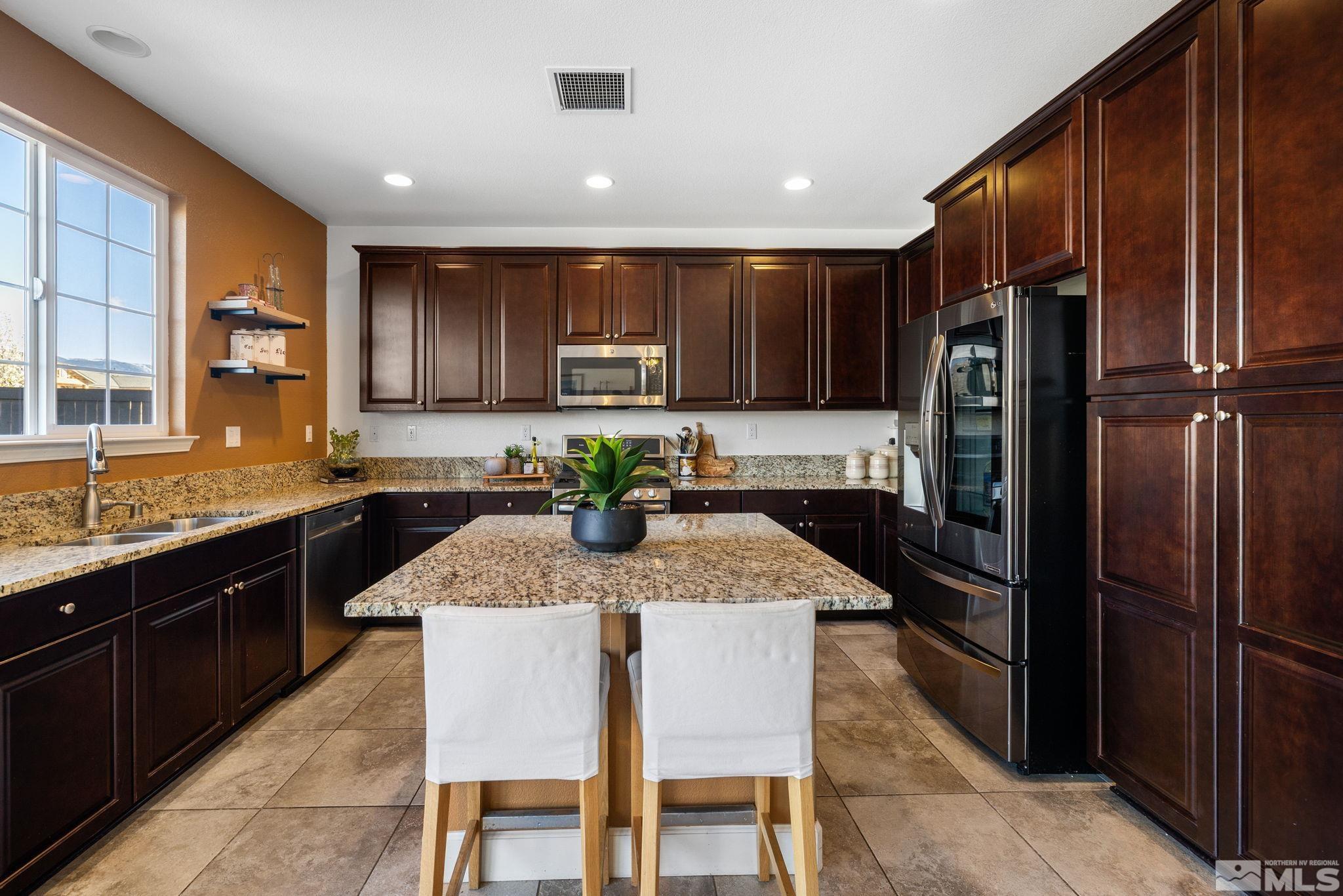 10656 Foxberry Park Drive Reno, NV 89521 - Photo 11 of 31 a kitchen with kitchen island granite countertop wooden cabinets a refrigerator a stove a microwave and island