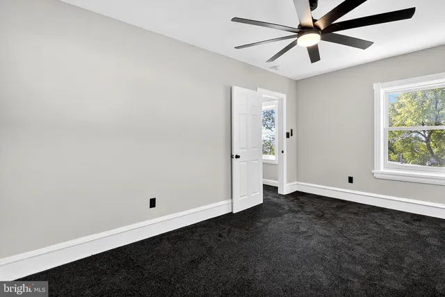 an empty room with a window and a fan