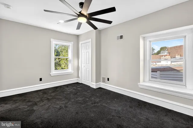 an empty room with windows and fan