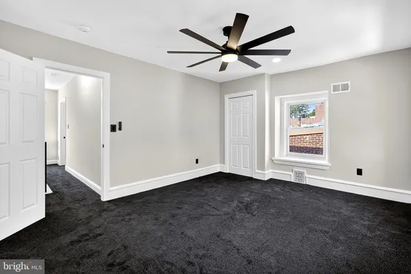 a view of an empty room with wooden floor and a ceiling fan