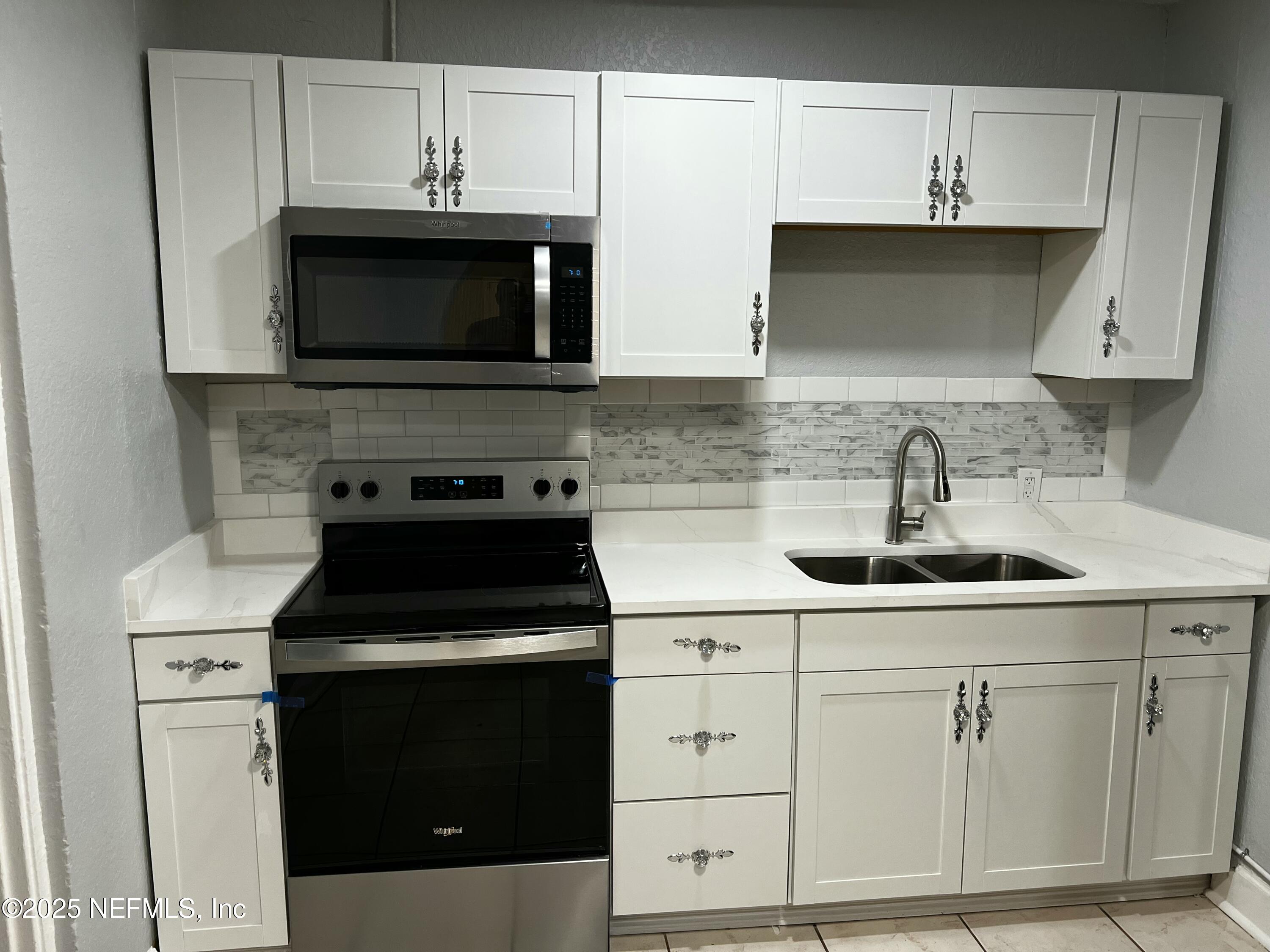 1826 Forest Hills Road Jacksonville, FL 32208 - Photo 5 of 14 a kitchen with white cabinets and black appliances