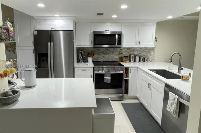 a kitchen with a sink a microwave a refrigerator and cabinets