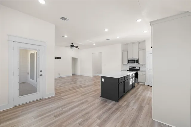 a kitchen with stainless steel appliances granite countertop a refrigerator and a wooden floors