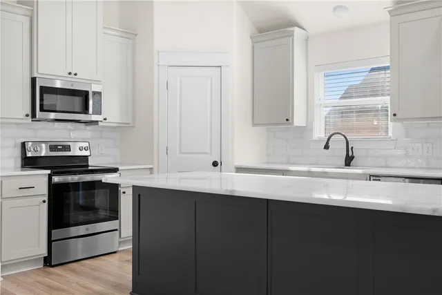 a kitchen with stainless steel appliances a sink a stove and microwave