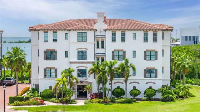 a front view of multi story residential apartment building with yard and parking