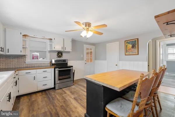 a kitchen with a stove a sink cabinets and wooden floor