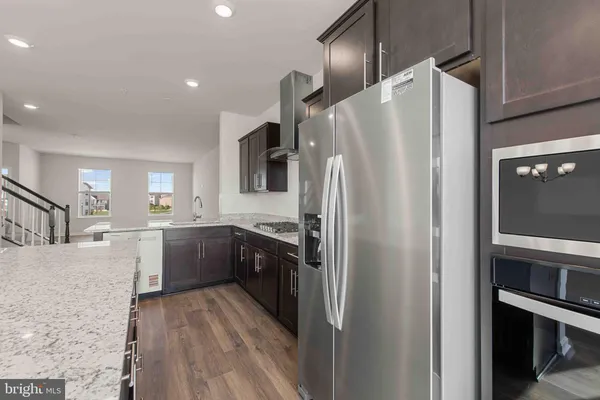 a kitchen with stainless steel appliances granite countertop a refrigerator a sink dishwasher a stove and white cabinets with wooden floor