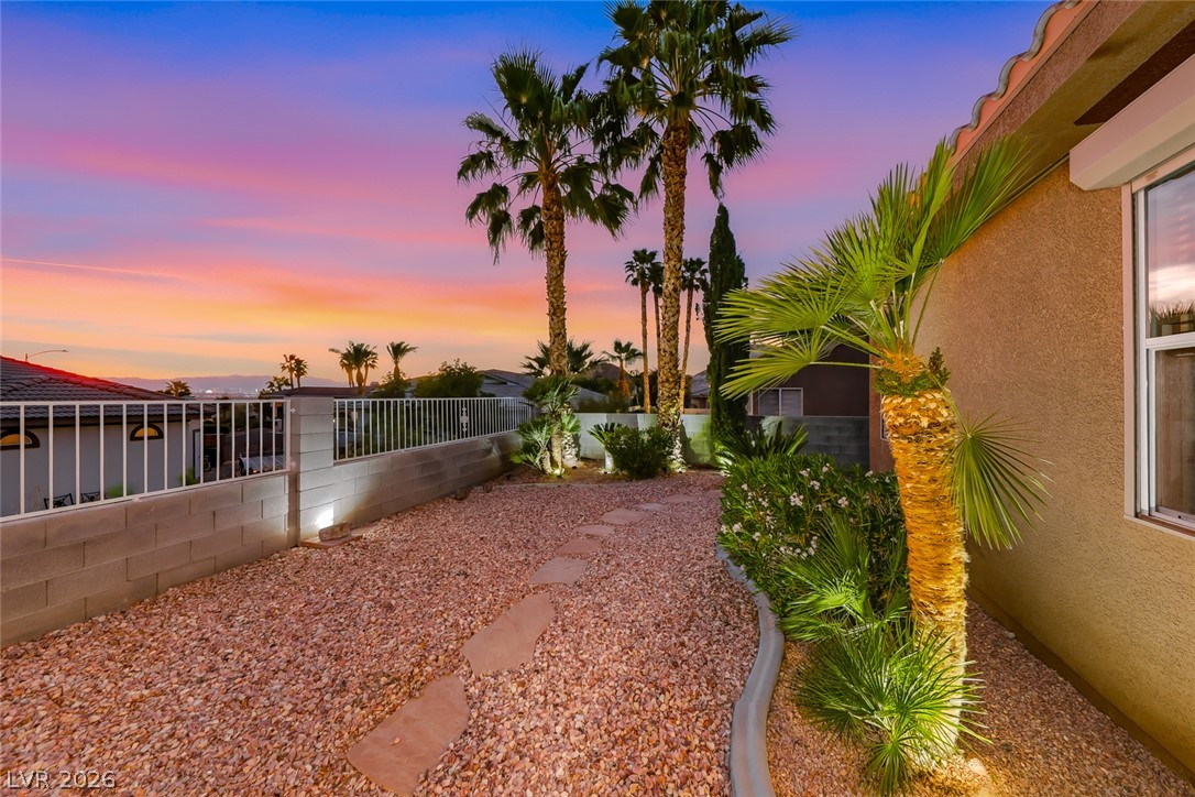 1104 Norellat Road Henderson, NV 89011 - Photo 44 of 52 A stone pathway meanders through low-maintenance desert landscaping framed by palm trees and western sunset views.