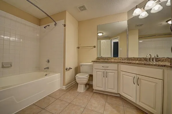 a spacious bathroom with a granite countertop sink a toilet mirror and shower
