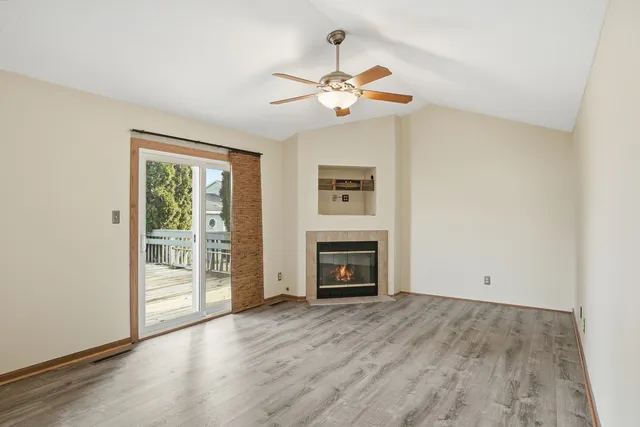 an empty room with wooden floor fireplace and windows