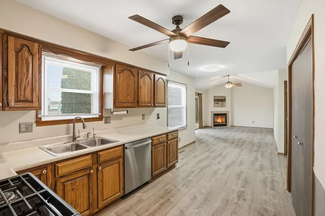 a kitchen with stainless steel appliances granite countertop a sink cabinets and wooden floor