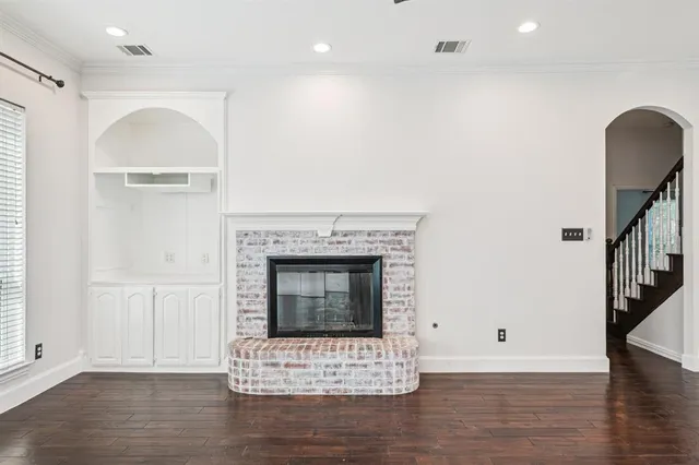 a view of an empty room with wooden floor and a fireplace