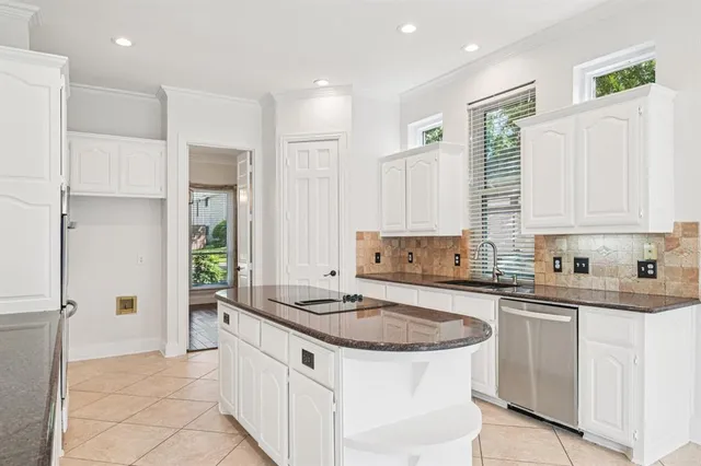 a kitchen with white cabinets and sink