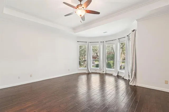 an empty room with wooden floor fan and windows